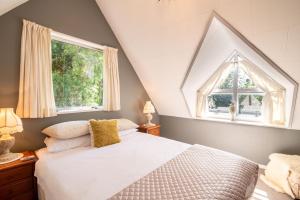 a bedroom with a white bed and two windows at HH Akaroa - Akaroa Holiday Home in Akaroa