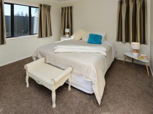 1 dormitorio con cama, banco y ventanas en Te Awa Napier Treasure - Napier Holiday Home, en Napier