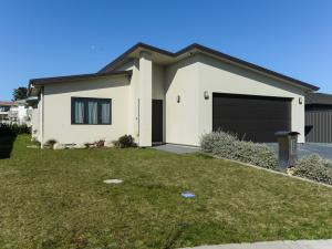 une maison blanche avec un garage dans l'établissement Te Awa Napier Treasure - Napier Holiday Home, à Napier