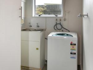 a small bathroom with a sink and a washing machine at Blue Lagoon - Kaiteriteri Holiday Unit in Kaiteriteri +8 photos