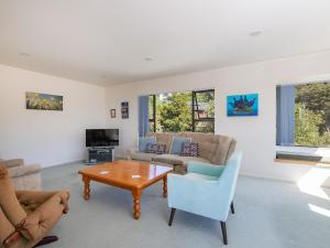 a living room with a couch and a table at Kawau Vista - Snells Beach Holiday Home in Snells Beach