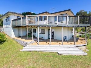 a large house with a large deck on top of it at Kawau Vista - Snells Beach Holiday Home in Snells Beach