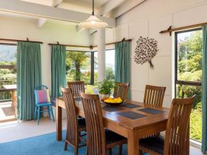 a dining room with a wooden table and chairs at Serene Sounds - Anakiwa Holiday Home in Anakiwa