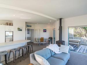 ein Wohnzimmer mit einem blauen Sofa und einer Küche in der Unterkunft Beachfront Getaway - Waikanae Beach Holiday Home in Waikanae