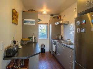 uma cozinha com um frigorífico de aço inoxidável e um lavatório em Raisin Town - Marahau Bach em Marahau