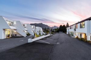 an empty parking lot with white buildings and mountains at Amity Serviced Apartments in Queenstown