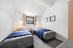 two beds in a room with white walls at Amity Serviced Apartments in Queenstown