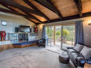 a living room with a couch and a tv at Tasman Hideaway - Marahau Holiday Home in Marahau