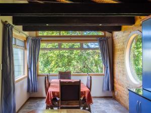 a dining room with a table and a large window at Tasman Hideaway - Marahau Holiday Home in Marahau