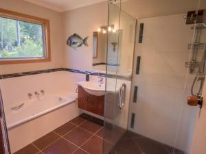 a bathroom with a tub and a sink and a shower at Tasman Hideaway - Marahau Holiday Home in Marahau +22 photos