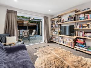 a living room with a tv and book shelves at The Hillvue with Spa - Arrowtown Holiday Home in Arrowtown