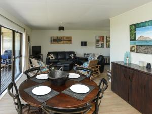 Bach 112 - Waimarama Holiday Home في Waimarama: غرفة طعام وغرفة معيشة مع طاولة وكراسي
