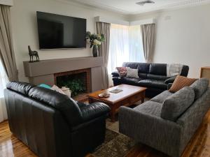 uma sala de estar com dois sofás e uma lareira em Harden Golfers Rest Accommodation em Harden