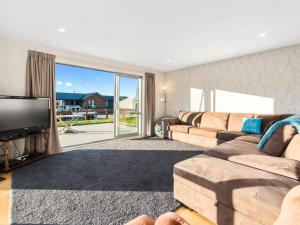 a living room with a couch and a flat screen tv at Pisa Oasis - Cromwell Holiday Home in Cromwell