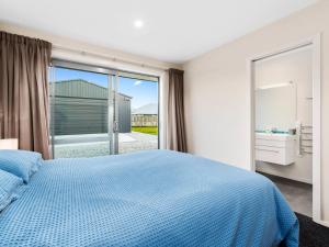 a bedroom with a blue bed and a large window at Pisa Oasis - Cromwell Holiday Home in Cromwell