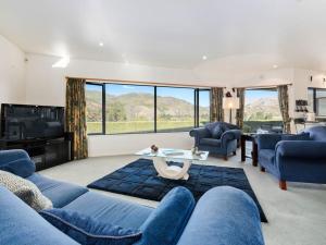 uma sala de estar com mobiliário azul e janelas grandes em Kawarau Bay View - Cromwell Holiday Home em Cromwell