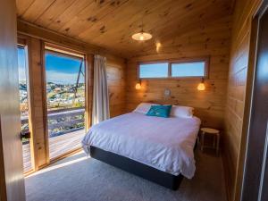 a bedroom with a bed and a large window at Beach House on the Ridge - Kaiteriteri House in Kaiteriteri