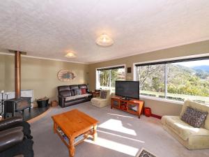 ein Wohnzimmer mit einem Sofa, einem TV und einem Tisch in der Unterkunft Mahakipawa Hideaway - Marlborough Sounds Home in Havelock