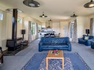 a living room with a blue couch and a wood stove at The Bellbird's Nest - Takamatua Holiday Home in Akaroa