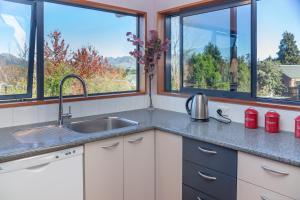 a kitchen with a sink and two windows at Hanmer's Rose - Hanmer Springs Holiday Home in Hanmer Springs