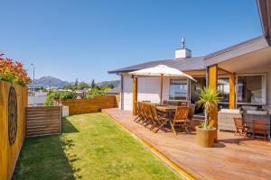 a backyard with a wooden deck with a table and chairs at Lakeside Luxury - Wanaka Holiday Home in Wanaka
