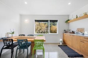 a kitchen with a wooden table and green chairs at The Bunkhouse - The Lodge Te Horo in Te Horo