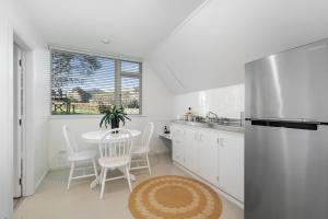 a kitchen with a table and a stainless steel refrigerator at The Apartment - The Lodge Te Horo in Te Horo