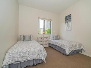 Un dormitorio con dos camas y una ventana. en Lakeside Villa Retreat - Matarangi Downstairs Unit, en Matarangi