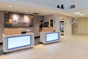 a man standing in a lobby with two monitors at Holiday Inn Express & Suites Raleigh NE - Medical Ctr Area, an IHG Hotel in Raleigh