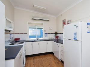 una cucina con mobili bianchi e un frigorifero bianco di Fingal Beach Shack a Fingal Bay Altre 9 foto