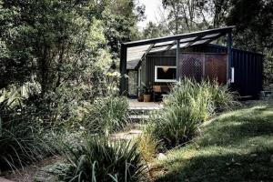 uma pequena casa preta com um alpendre num jardim em Dark Moon Cottage. Luxurious. em Yandina Creek