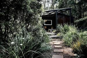 um caminho de jardim que leva a uma cabana preta em Dark Moon Cottage. Luxurious. em Yandina Creek