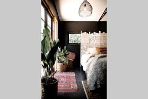 um quarto com uma cama e plantas nele em Dark Moon Cottage. Luxurious. em Yandina Creek