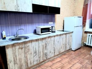 a kitchen with a counter with a microwave and a refrigerator at Яновского 2к in Kropyvnytskyi