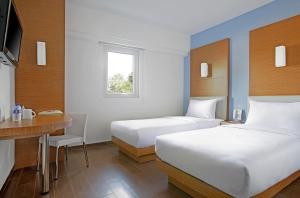 una camera d'albergo con due letti e una scrivania di Amaris Hotel Cirebon a Cirebon