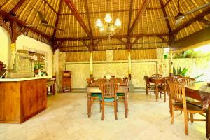 a dining room with tables and chairs and a chandelier at Manzelejepun Villa & Pavilion in Sanur