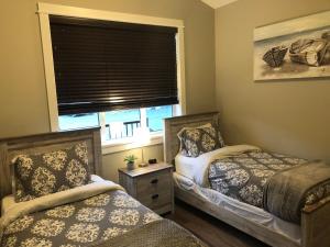 two beds in a small room with a window at Sandy Feet Retreat Port Renfrew- Oceanfront 2BR modern cottage in Port Renfrew