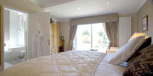 a white bed sitting in a bedroom next to a window at Tyn Rhos Country House in Caernarfon