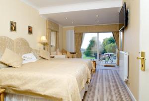 a hotel room with two beds and a television at Tyn Rhos Country House in Caernarfon