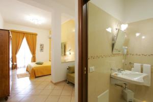 a bathroom with a sink and a bedroom with a bed at H- Rooms La Darsena in San Vito lo Capo