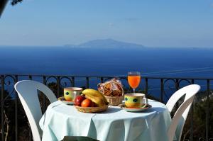 einen Tisch mit einer Schale Obst und einem Glas Saft in der Unterkunft Le Ginestre di Capri BB & Holiday House in Anacapri