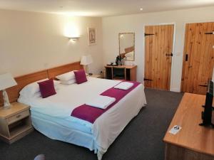 a bedroom with a large bed with two pillows on it at The Flying Fish Stables in Ilminster