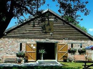 a barn with wooden doors and a building at The Flying Fish Stables in Ilminster
