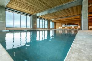 une piscine intérieure avec un plafond en bois et des baies vitrées dans l'établissement LE RIDGE Résidence Premium - Les Arcs Paradiski, à Arc 1600