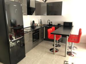 a kitchen with a black counter and red chairs at Apartament Telkom 2 in Milówka