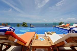 a swimming pool with a table and chairs and the ocean at Season Paradise in Thulusdhoo