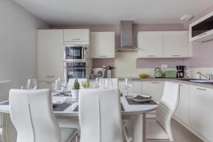 una cocina con una mesa con armarios blancos y sillas blancas en Rose des Vents, en Damgan