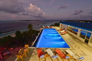a swimming pool with chairs and the beach at Season Paradise in Thulusdhoo