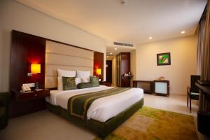 ein Hotelzimmer mit einem großen Bett und einem TV in der Unterkunft Nine Tree Luxury Hotel & Suites Lahore in Lahore