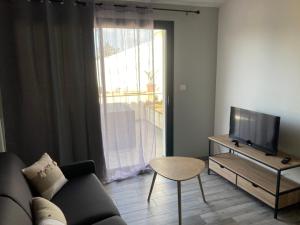 a living room with a couch and a tv and a table at studio meublé du bourg in Puymiclan